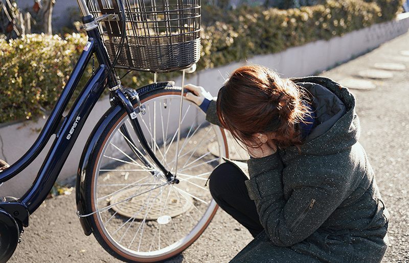 自転車のタイヤの空気を確認する女性