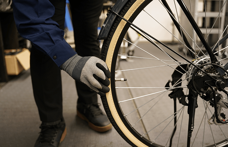 自転車のタイヤの空気圧を確認するスタッフ