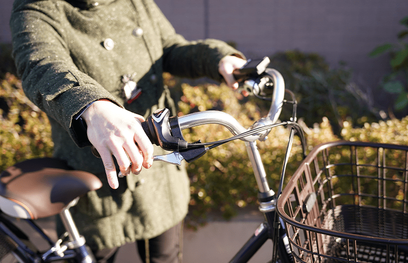 女性が自転車のブレーキを握る