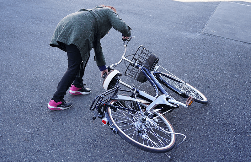 倒れている自転車を起こしている女性