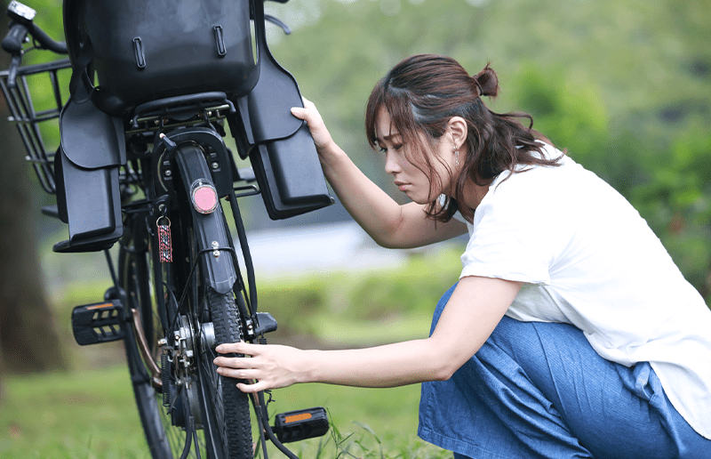 自転車のタイヤを確認する女性